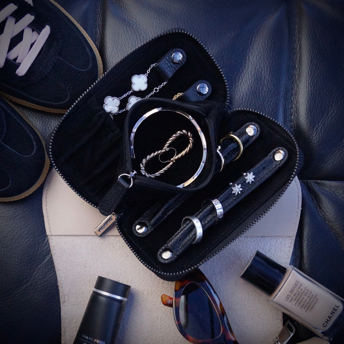 Jewellery organised inside a jewellery case that is on top of a handbag along with other accessories.