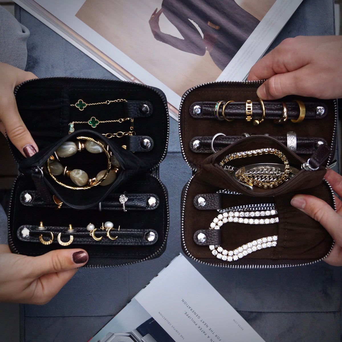 Two leather travel cases with jewellery inside and magazines in background.