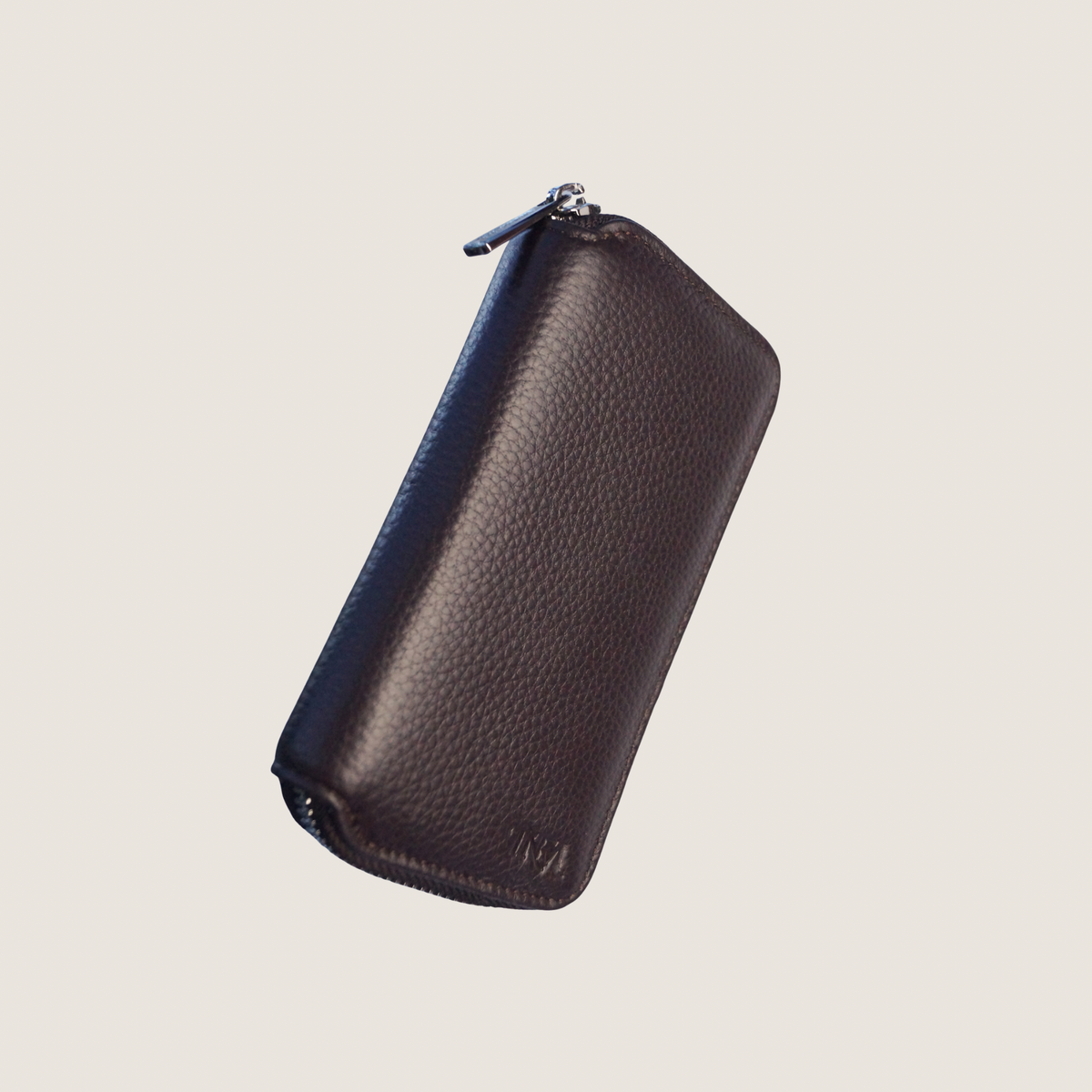 Small brown leather jewellery travel case with beige background.