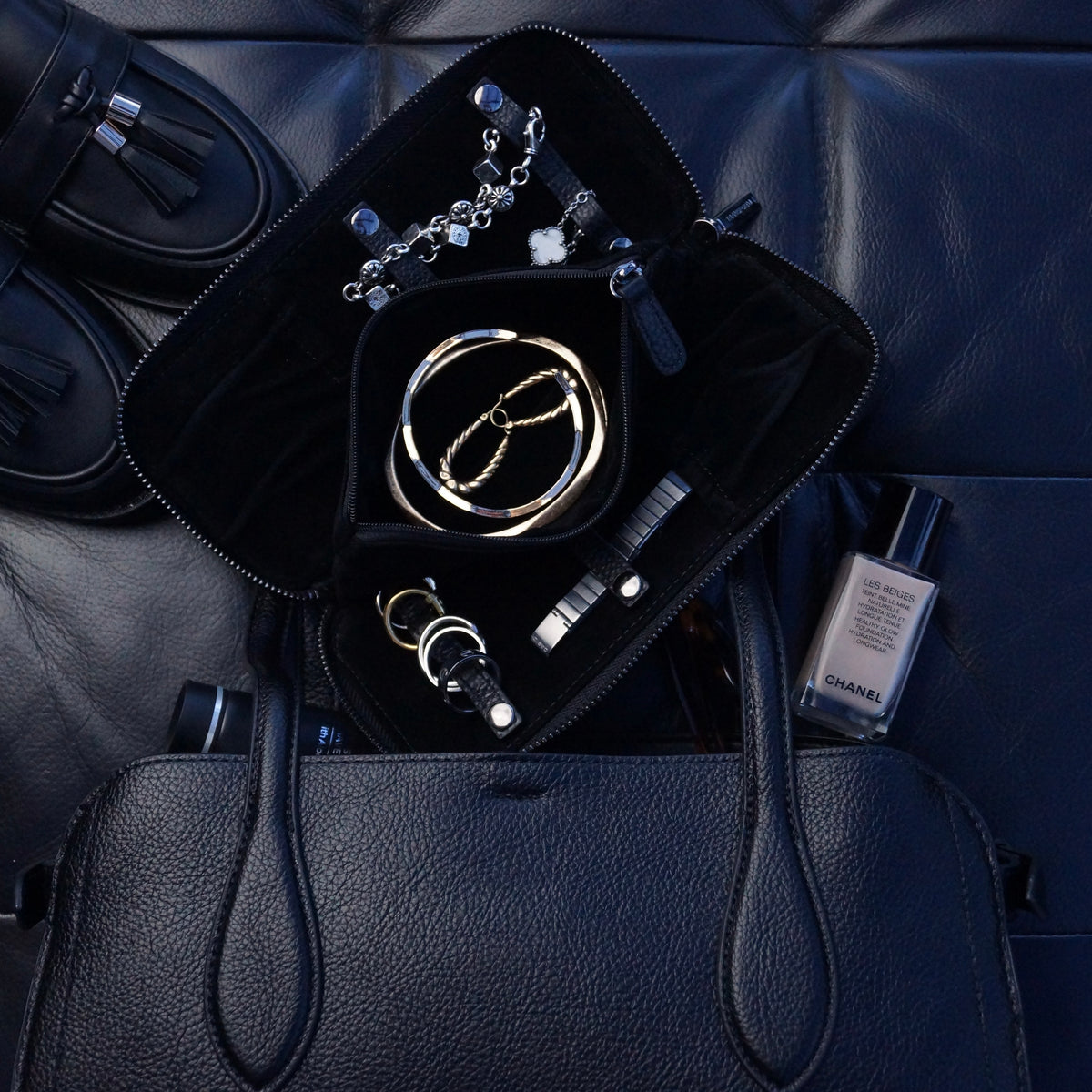 Various pieces of jewellery inside a large jewellery case sat on a handbag.