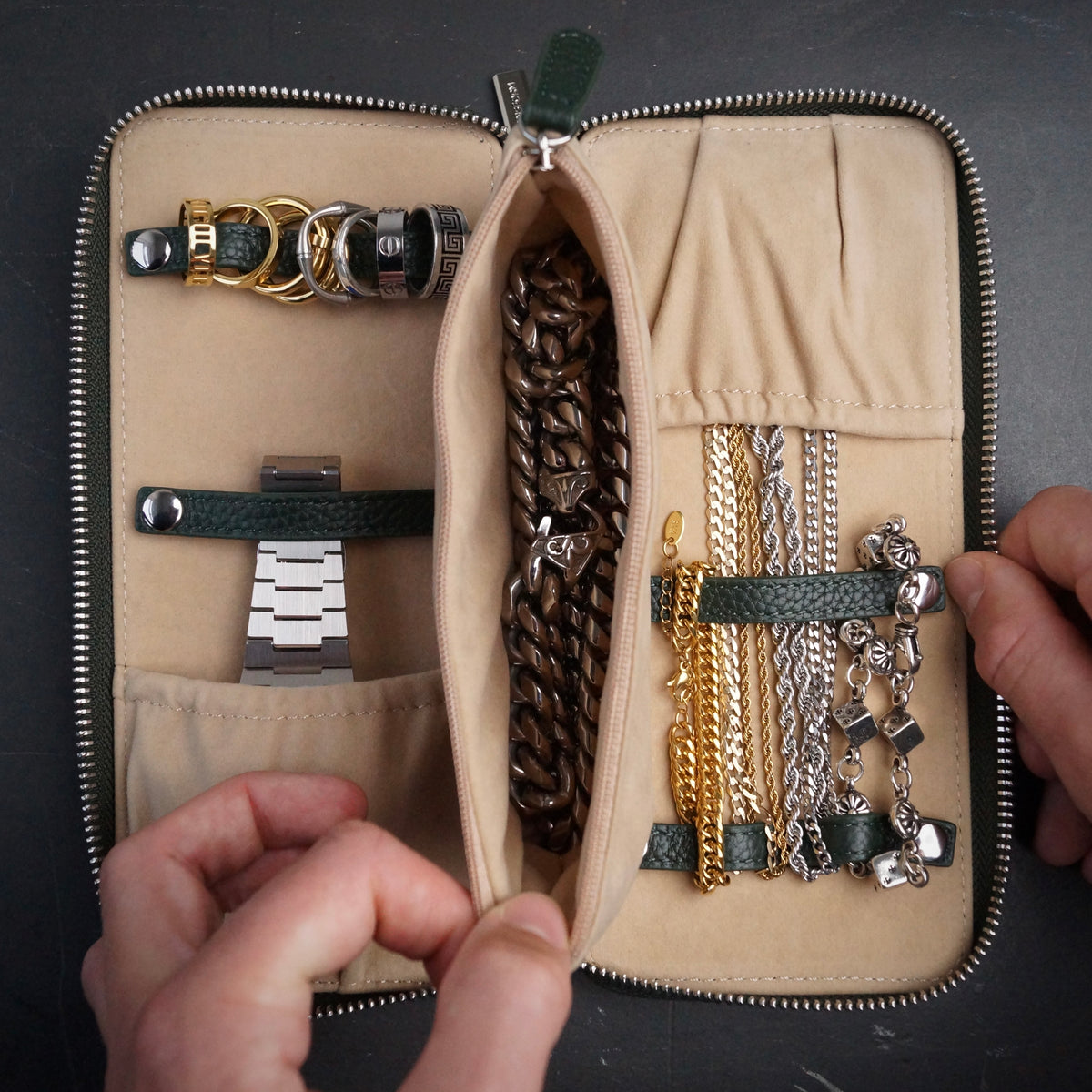 Dark green and beige jewellery organiser with necklaces and bracelets on a dark background.