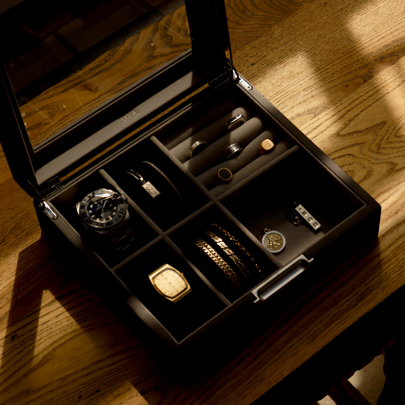 Bird’s-eye lifestyle view of the LDN IV men’s 4-slot black watch box by Transform, filled with two watches, necklaces, bracelets, cufflinks and other accessories.