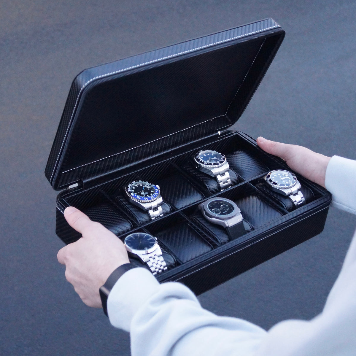 Bird’s-eye lifestyle view of the Stealth X men’s 10-slot carbon watch case by Transform, held by a man and filled with watches.