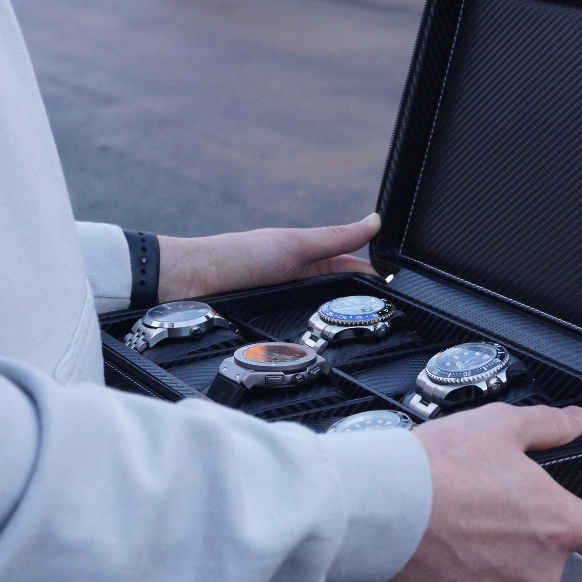 Side on view of the Stealth X men’s 10-slot carbon watch case by Transform, held by a man and filled with watches.