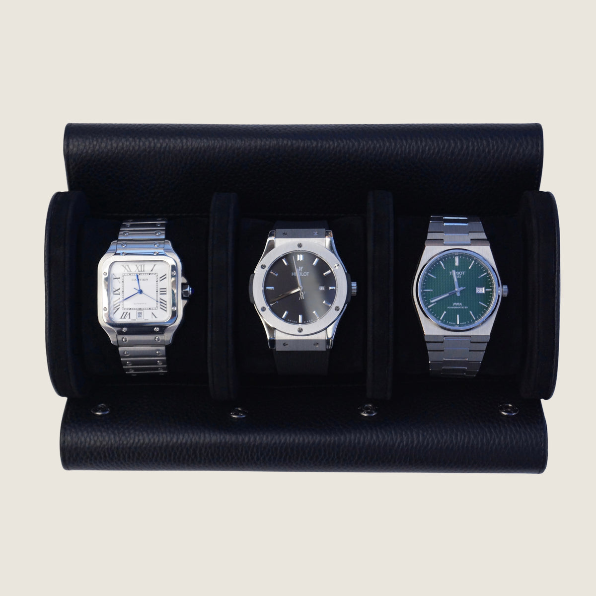 Three watches inside a black leather watch roll on a beige background.