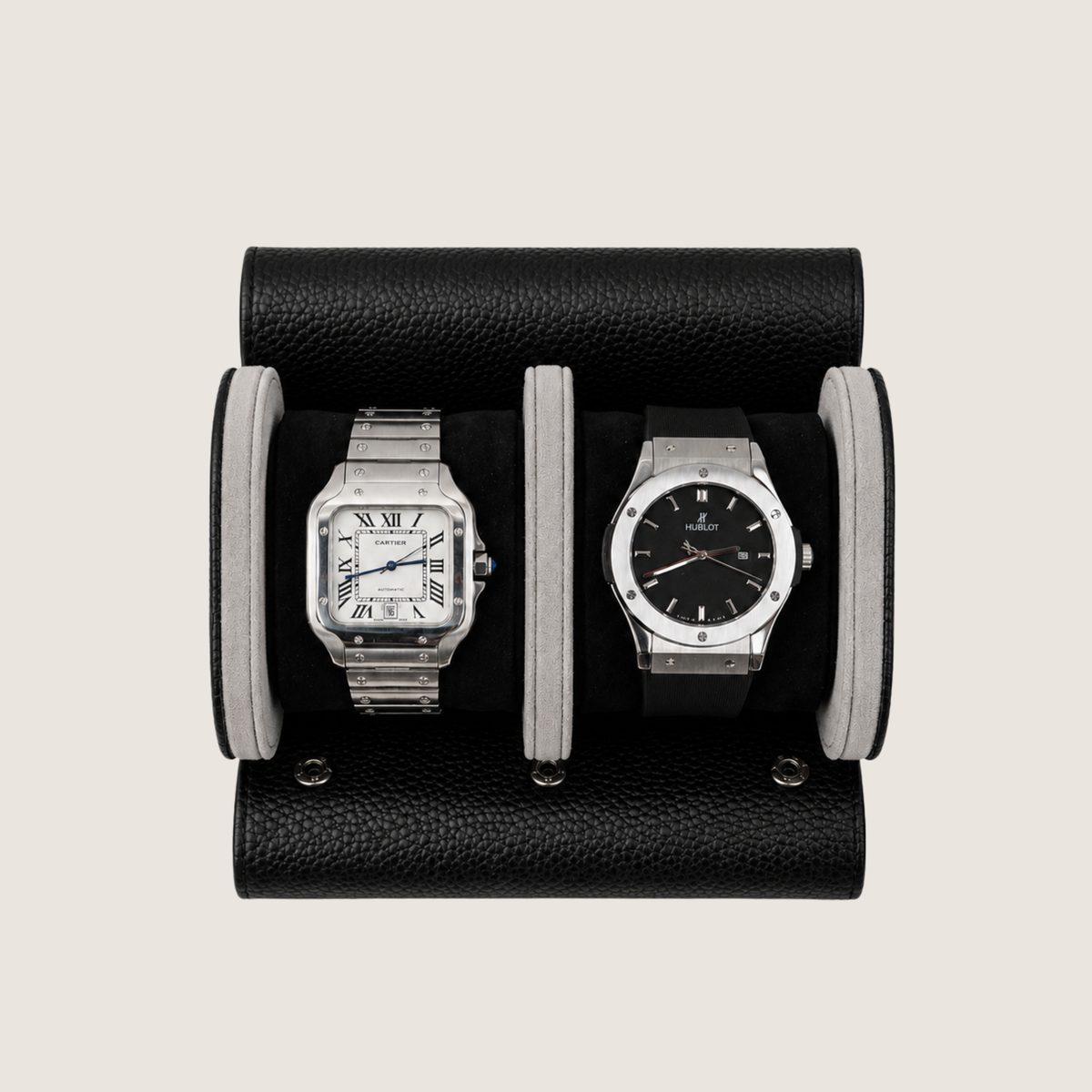 Two wristwatches displayed side by side in a black leather watch roll on a light beige background.