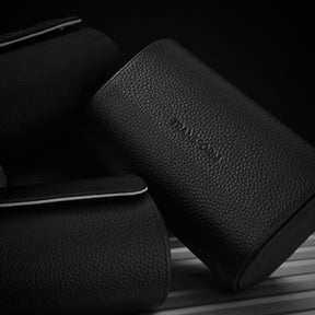 Three black pebbled leather watch rolls arranged on a dark studio background, with one case prominently showing the debossed brand name 'Transform'.