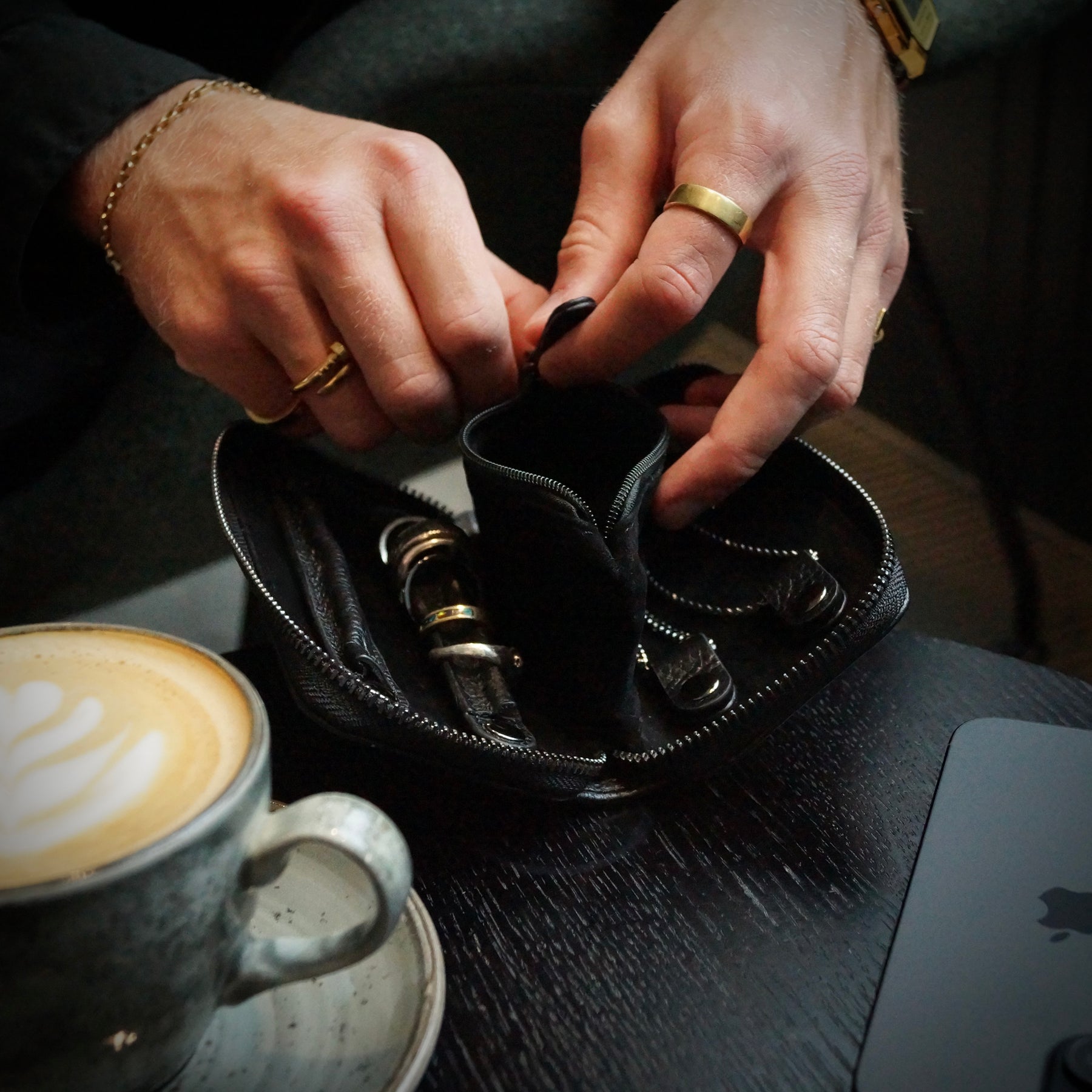 Hands closing the middle pouch of a black jewellery case.