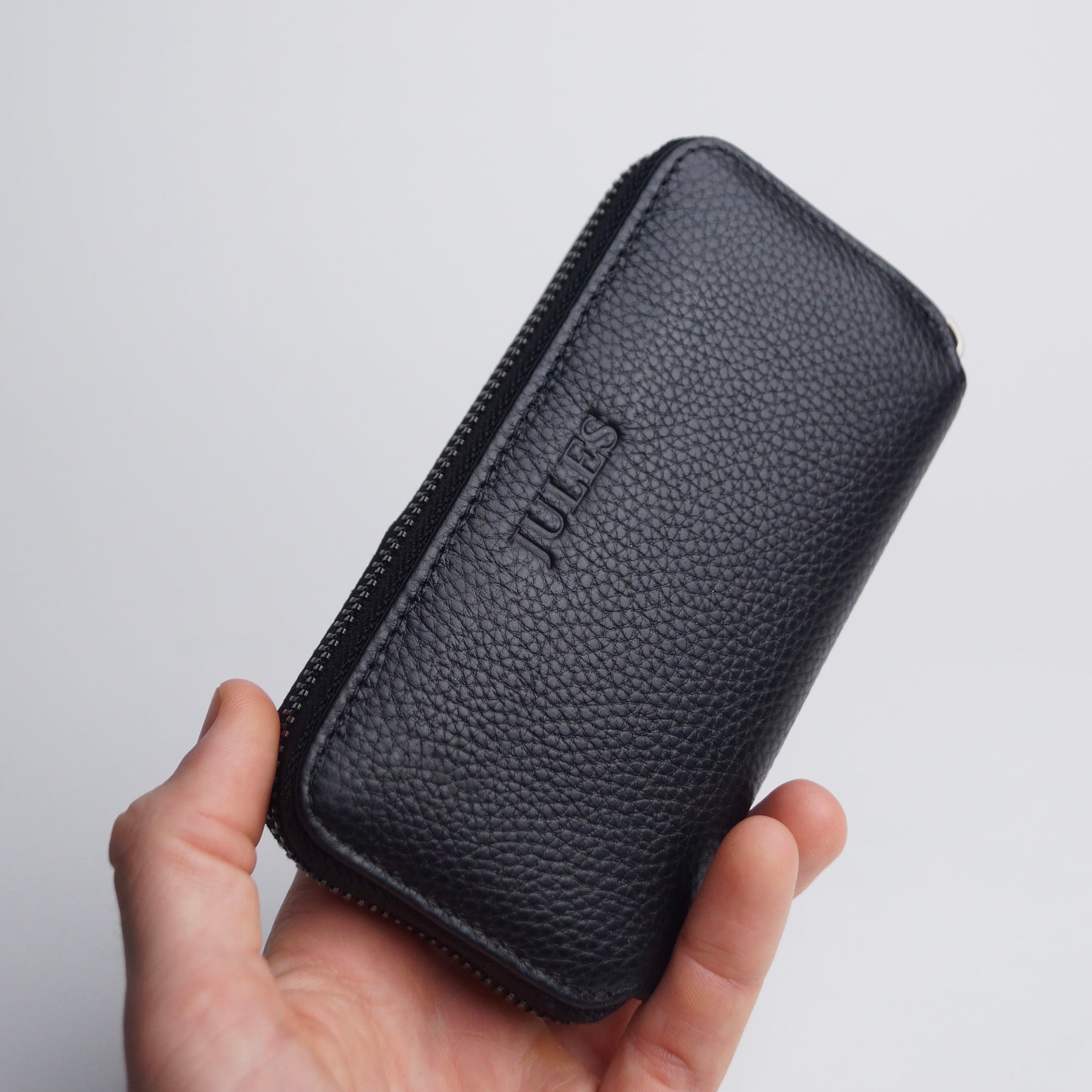 Hand holding personalised black leather jewellery travel case.