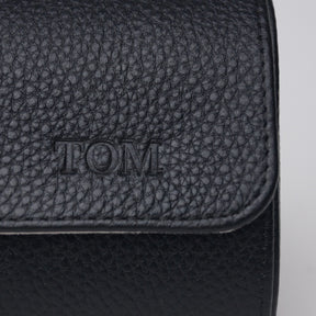 Close-up of a black leather watch roll with 'Tom" engraved into the leather.
