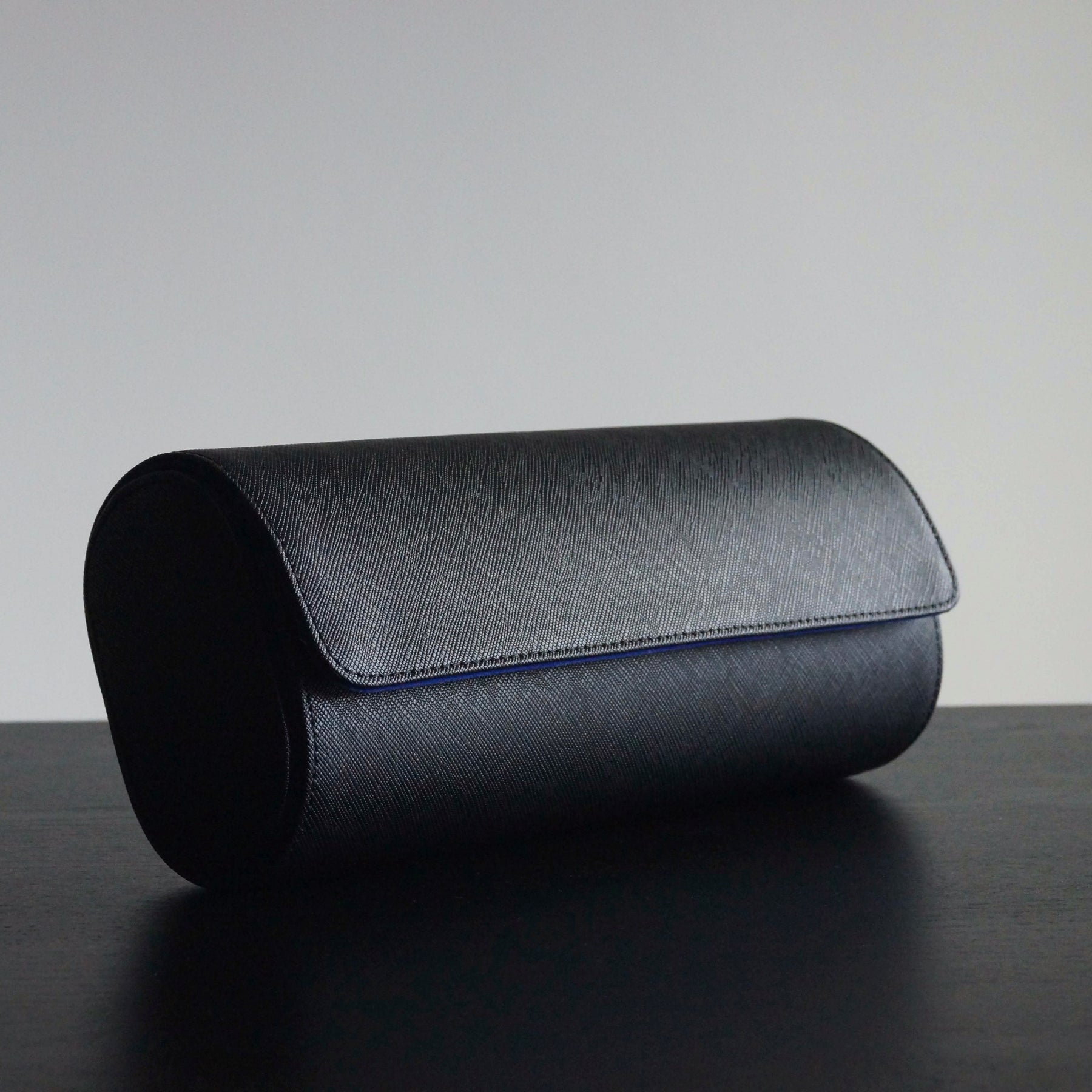 Side view of a leather 3-slot Transform watch roll closed on a table.