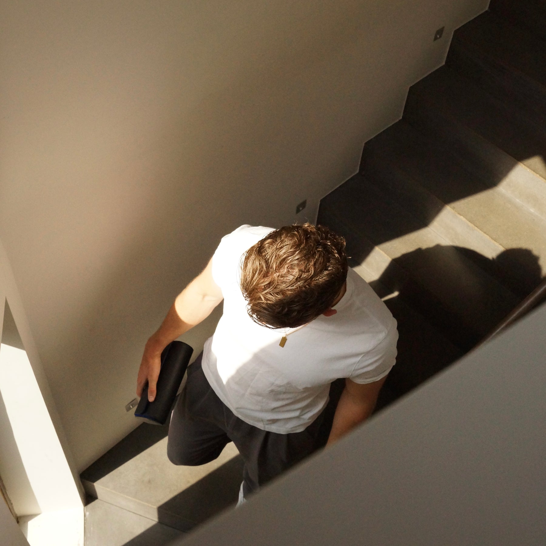 Lifestyle image of a man walking down a staircase holding a leather watch roll.