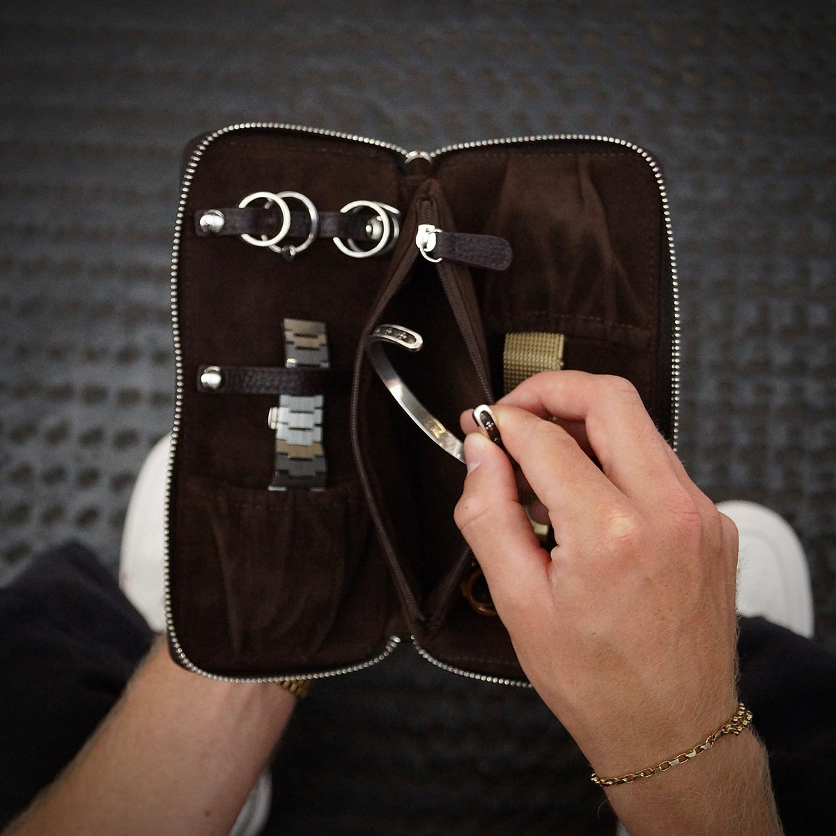 Hands taking a bangle out of a jewellery travel case from a birds eye view.