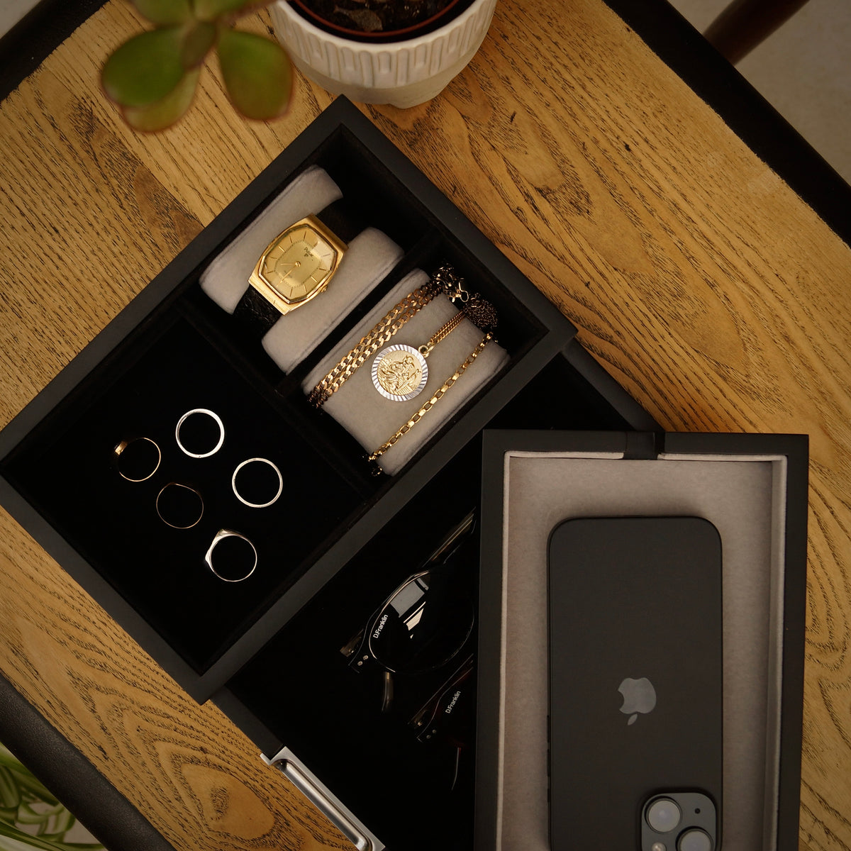 Black LDN II men’s watch, jewellery and accessory organiser by Transform in a bird’s eye close-up view, filled with a watch, rings, necklace, bracelet, glasses and a phone.