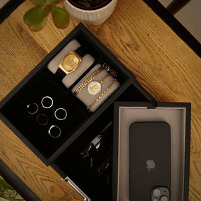 Black LDN II men’s watch, jewellery and accessory organiser by Transform in a bird’s eye close-up view, filled with a watch, rings, necklace, bracelet, glasses and a phone.