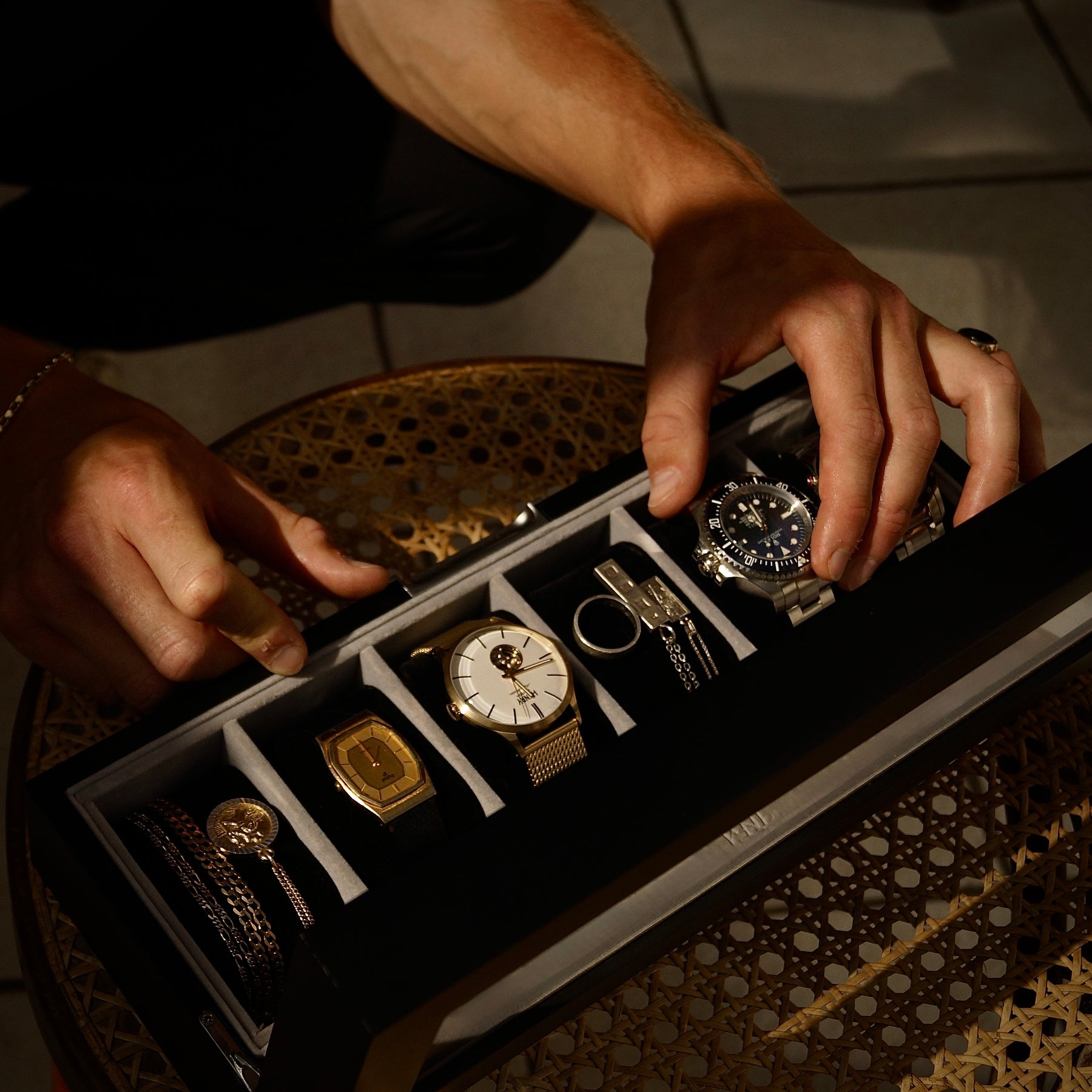Person taking a watch out of a 6 slot watch box.