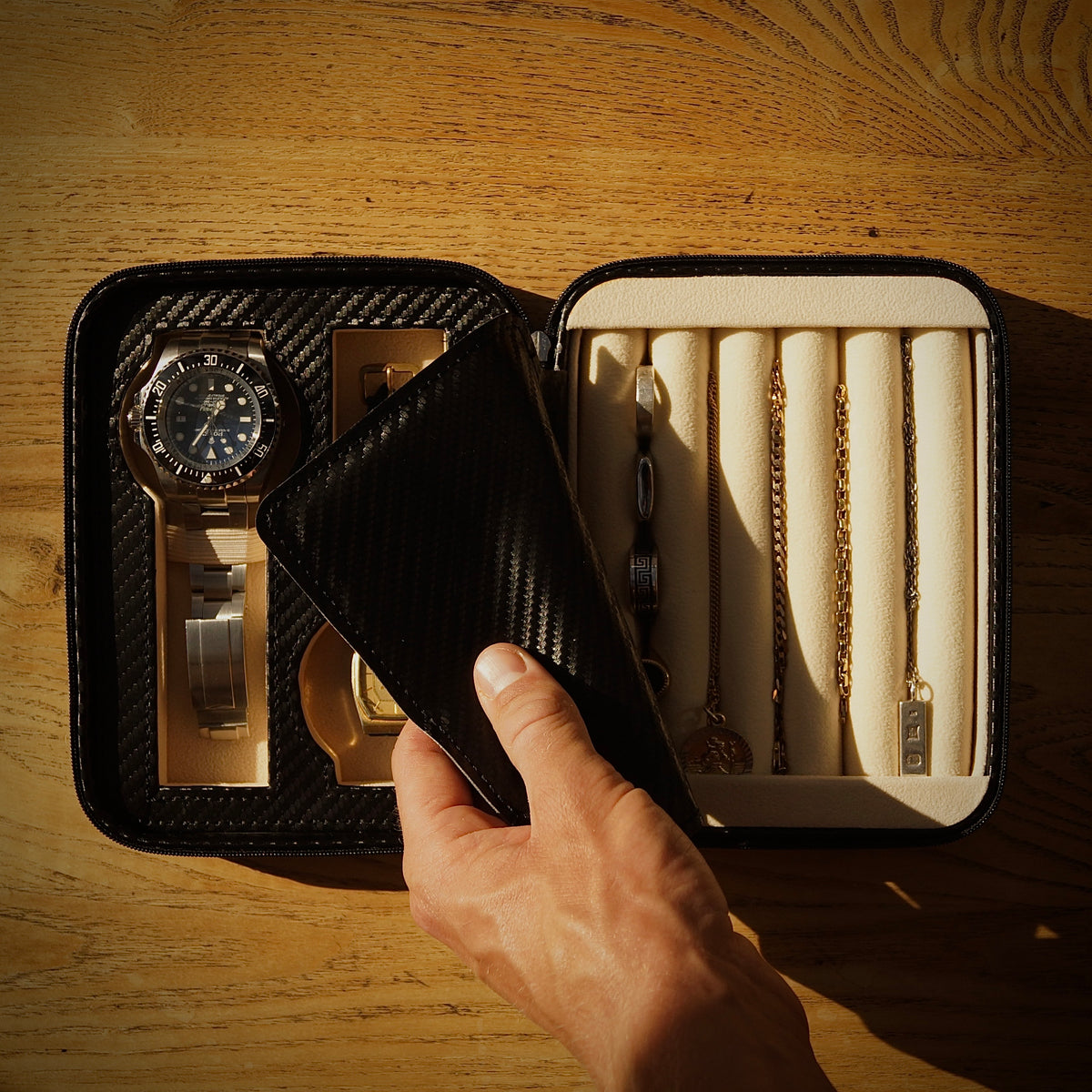 Bird’s-eye lifestyle view of the Stealth II men’s 2-slot watch and jewellery case by Transform, held by a man and filled with two watches, necklaces, bracelets, cufflinks and rings.