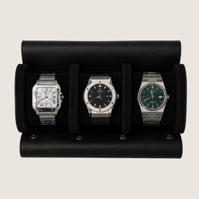 Three wristwatches displayed side-by-side in a black leather watch roll against a light beige background.