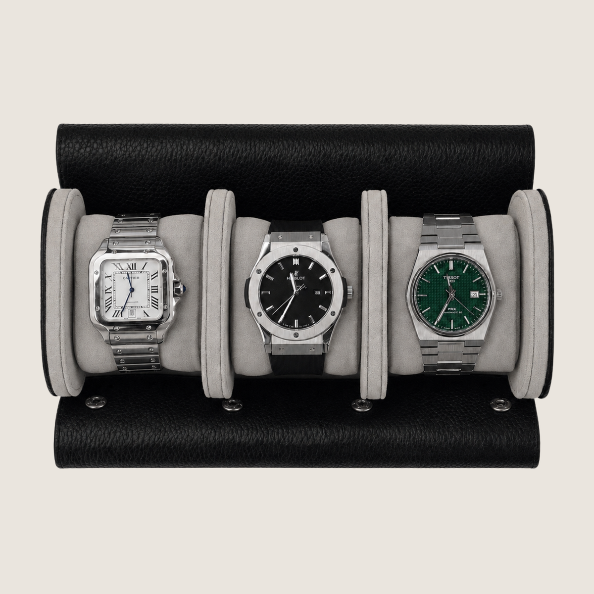 Three wristwatches displayed side by side inside a black leather watch roll with light gray fabric cushions, photographed from above on a plain light beige background.