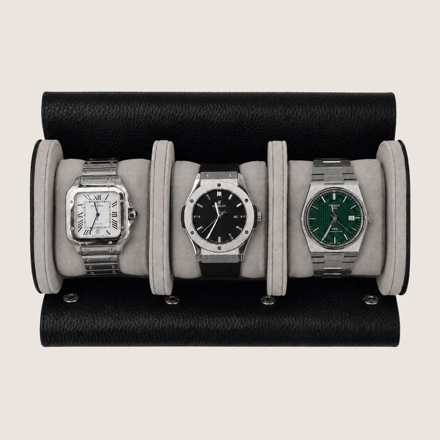 Three wristwatches displayed side by side inside a black leather watch roll with light gray fabric cushions, photographed from above on a plain light beige background.