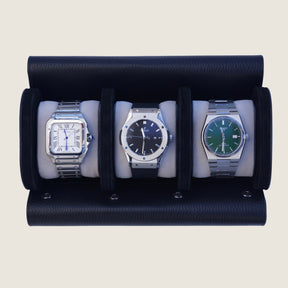 Three watches inside a black and grey leather watch roll with a beige background.