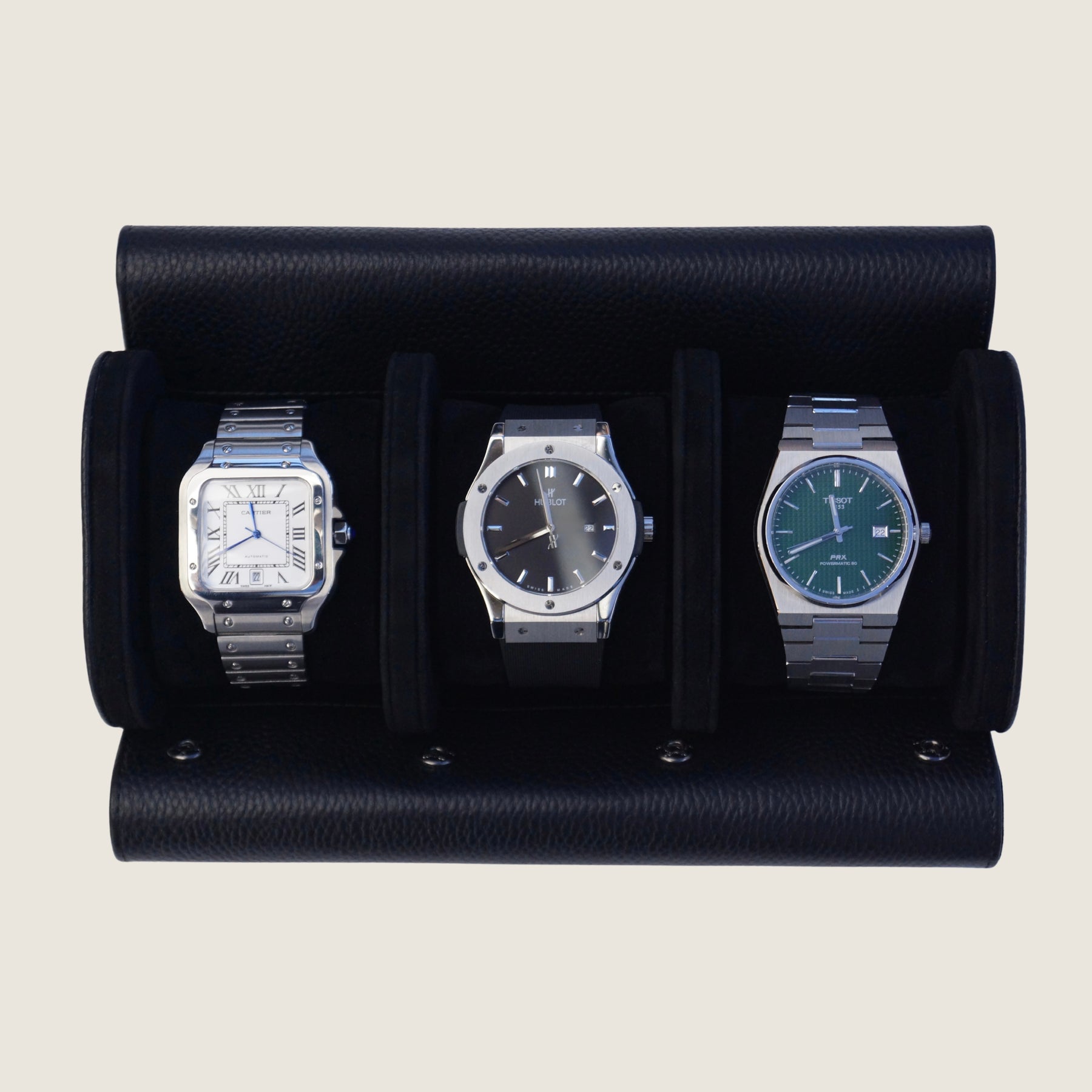 Three watches inside a black leather watch roll on a beige background.