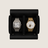 Two wristwatches displayed side-by-side in a black textured leather watch roll.